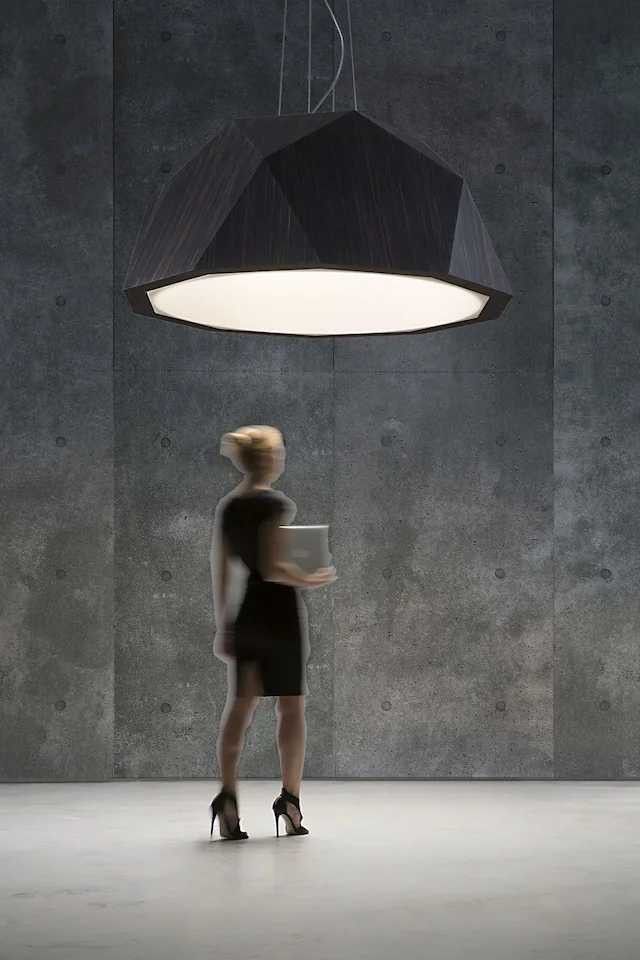 revestimento de parede mineral zen ando cement amba em ambiente de pé-direito alto com luminária suspensa geométrica e figura humana para escala